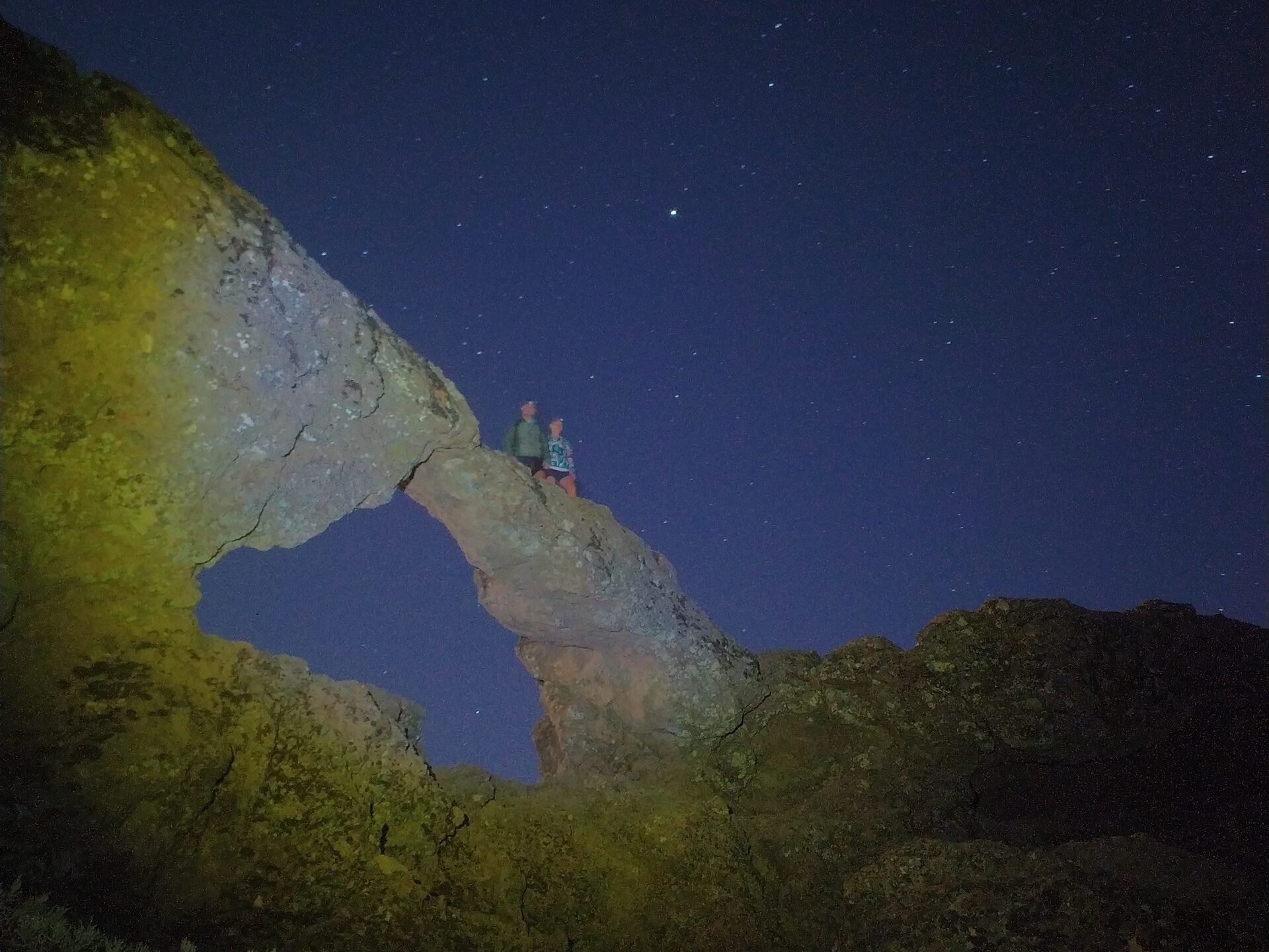 a group of people standing on a rock while star gazing