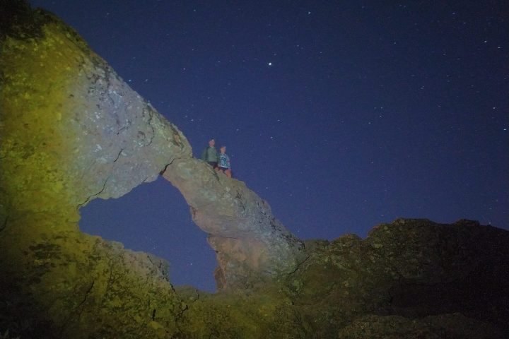 a group of people standing on a rock while star gazing