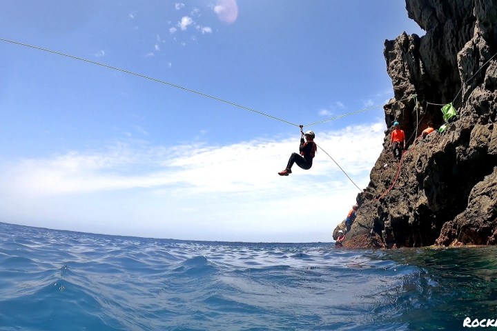 a person ziplining from rocky cliffs