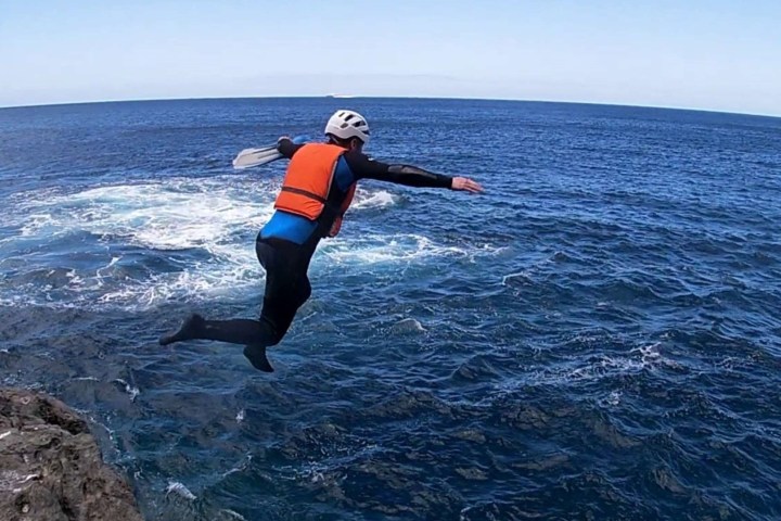 a person jumping off a rocky cliff for a sea dive