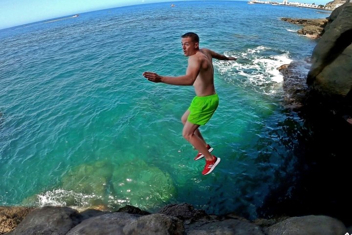 a person jumping off a rocky cliff for a sea dive
