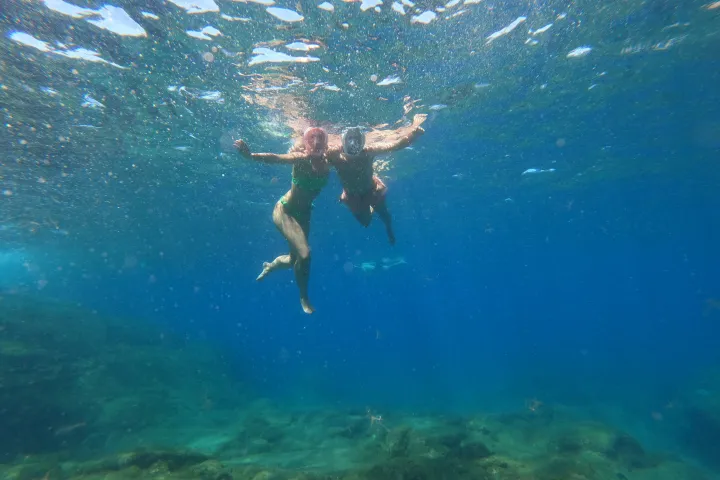 a man flying through the air while swimming in a body of water