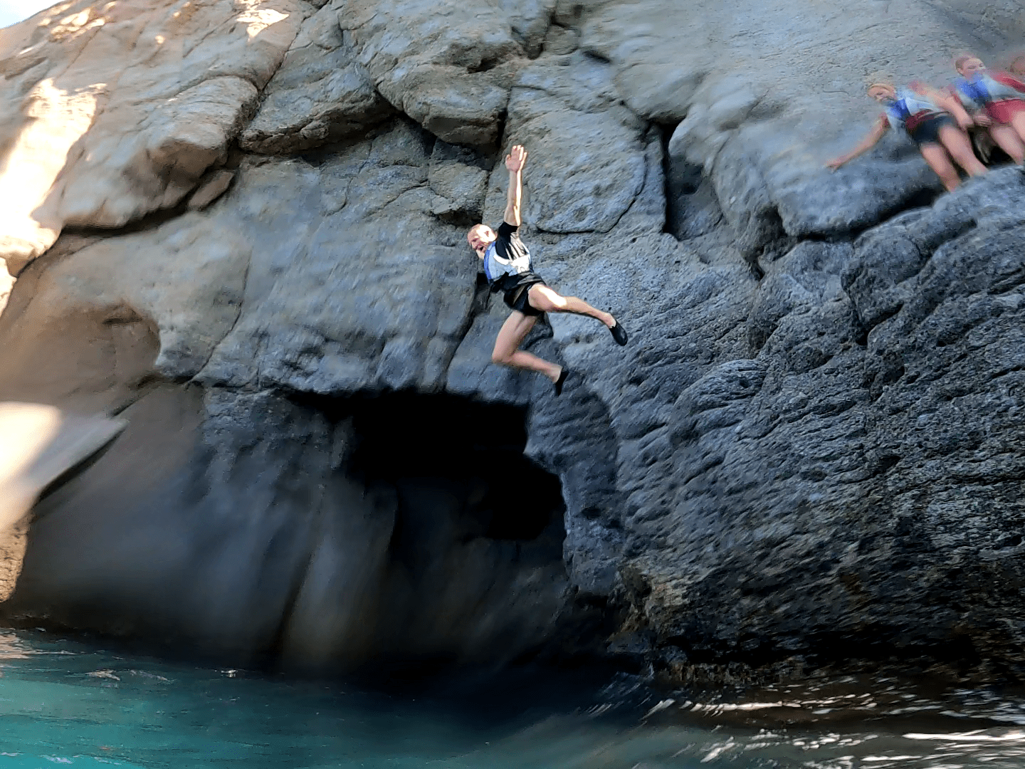 a person swimming in water next to the rock