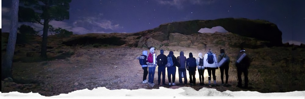 a group of people standing in front of a mountain